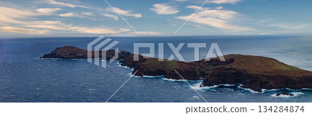 Wide panoramic view of Ponta de Sao Lourenco, Madeira, Portugal. Rust colored volcanic cliffs meet white edged waves, sparse vegetation, daytime, horizontal composition. Wide panoramic view of Ponta de Sao Lourenco, Madeira, Portugal. Rust colored volcanic cliffs meet white edged waves, sparse vegetation, daytime, horizontal composition. 134284874
