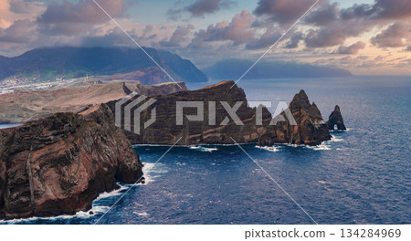 Rugged cliffs and sea stacks meet strong surf at Ponta de Sao Lourenco, Madeira, Portugal. Wide view from a high vantage in soft evening light with deep blue water. Rugged cliffs and sea stacks meet strong surf at Ponta de Sao Lourenco, Madeira, Portugal. Wide view from a high vantage in soft evening light with deep blue water. 134284969