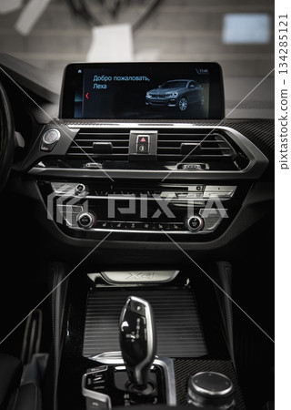 The BMW X4 dashboard features a modern design with a central screen displaying a welcome message in Russian, metallic accents, and a glossy finish. 134285121