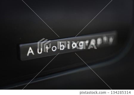 A close up shows the Autobiography badge on a glossy dark panel in a luxury car workshop. Soft lighting and shallow depth of field highlight premium branding. A close up shows the Autobiography badge on a glossy dark panel in a luxury car workshop. Soft lighting and shallow depth of field highlight premium branding. 134285314