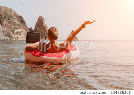 Woman, Beach, Relaxation: Woman relaxing on an inflatable tube in the sea on a sunny day. 134286308