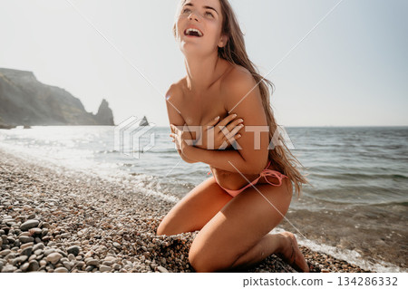 Young Woman in Pink Bikini on a Stony Beach 134286332
