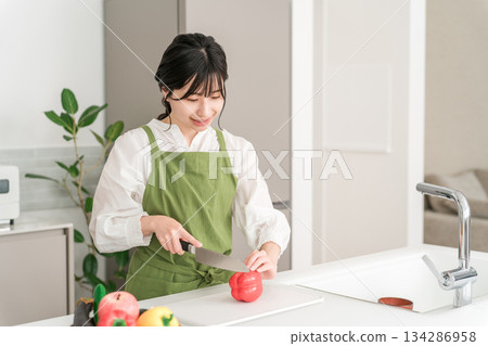 Young Asian woman in an apron cooking in the kitchen 134286958