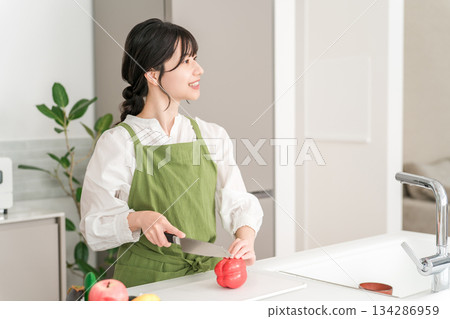Young Asian woman in an apron cooking in the kitchen 134286959