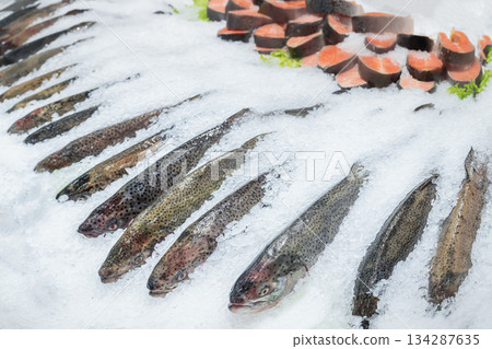 Trout, salmon or sockeye salmon - different types of fresh salmon on ice - fresh chilled red fish in a steam-cooled supermarket window. Raw salmon steaks , visual fish merchandising . High quality 134287635