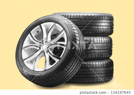 A set of summer wheels on a yellow background. A stack of summer tires with sleek alloy wheels showcases their sturdy design. These wheels provide enhanced braking and grip for safe driving A set of summer wheels on a yellow background. A stack of summer tires with sleek alloy wheels showcases their sturdy design. These wheels provide enhanced braking and grip for safe driving 134287645