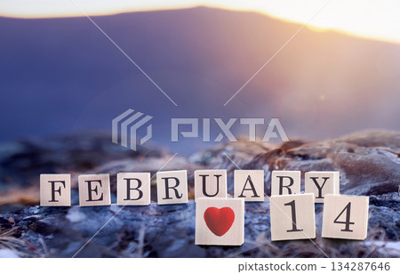 February 14 is the date of the Valentine's Day holiday made of wooden cubes on the background of blue mountains at sunset or sunrise. A beautiful representation of Valentines Day showcasing themes of February 14 is the date of the Valentine's Day holiday made of wooden cubes on the background of blue mountains at sunset or sunrise. A beautiful representation of Valentines Day showcasing themes of 134287646