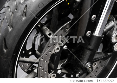 Detailed close-up view of a motorcycle front wheel, disc brake 134288092