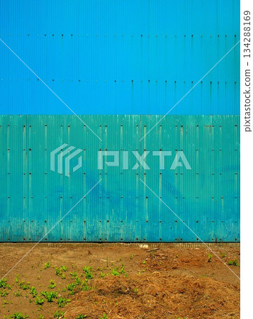 藍色波紋鐵皮牆和空曠的倉庫場地，用於存放材料。 134288169