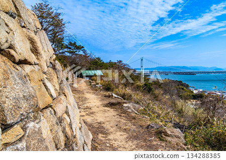 Stone walls of Shimotsui Castle ruins and Shimotsui Seto Bridge in early spring, Kurashiki City, Okayama Prefecture 134288385