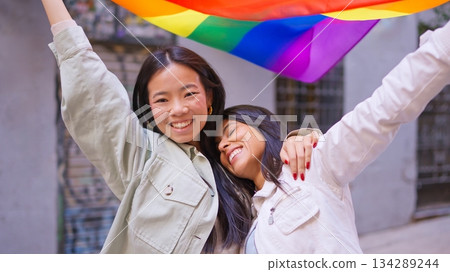 Smiling diverse women celebrating inclusion holding rainbow flag 134289244