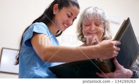 Granddaughter and grandmother woman smiling reviewing photo album 134289263