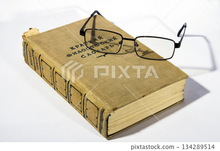 Philosophical dictionary and glasses lying on a white surface Philosophical dictionary and glasses lying on a white surface 134289514