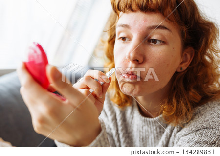 young woman looks at problematic facial skin in mirror 134289831