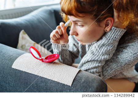 young woman looks at problematic facial skin in mirror young woman looks at problematic facial skin in mirror 134289942