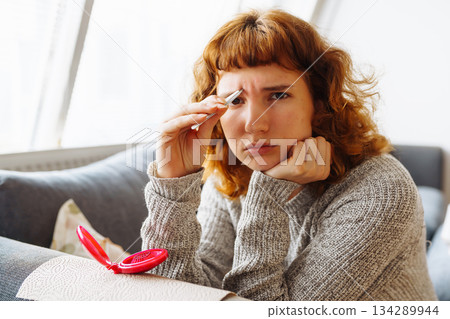 young woman looks at problematic facial skin in mirror young woman looks at problematic facial skin in mirror 134289944