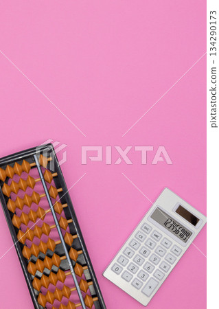 粉紅色背景上的算盤和計算機。圖片主題：計算、商業、教育 134290173