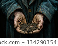 ageing wrinkled hands man dressed in an old denim jacket, stained with earth, hold soil 134290354