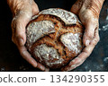 old hands with wrinkles, stained flour, hold round rye bread, low key, top view 134290355