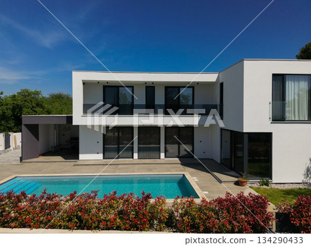 Aerial view of two stunning modern luxury villas with private swimming pools, elegant architecture, and lush green landscaping, set against a beautiful natural backdrop Aerial view of two stunning modern luxury villas with private swimming pools, elegant architecture, and lush green landscaping, set against a beautiful natural backdrop 134290433