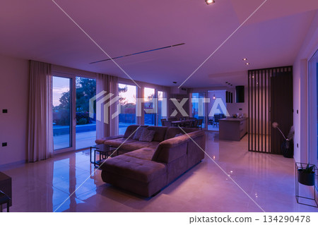 Modern, bright living room featuring a comfortable sofa and panoramic glass doors opening to a stunning private swimming pool and lush garden. Perfect for luxurious indoor-outdoor living Modern, bright living room featuring a comfortable sofa and panoramic glass doors opening to a stunning private swimming pool and lush garden. Perfect for luxurious indoor-outdoor living 134290478
