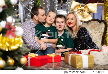 Portrait of happy family with two children celebrating Christmas next to Christmas tree Portrait of happy family with two children celebrating Christmas next to Christmas tree 134290493