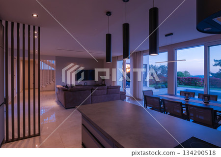 Modern, bright living room featuring a comfortable sofa and panoramic glass doors opening to a stunning private swimming pool and lush garden. Perfect for luxurious indoor-outdoor living Modern, bright living room featuring a comfortable sofa and panoramic glass doors opening to a stunning private swimming pool and lush garden. Perfect for luxurious indoor-outdoor living 134290518
