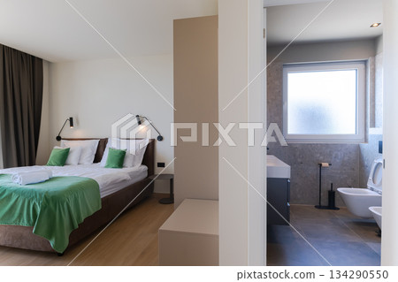 Modern open-plan living and dining room in a luxury villa with large glass doors opening to a private swimming pool, offering a spacious and elegant indoor-outdoor living experience 134290550