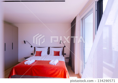 Modern open-plan living and dining room in a luxury villa with large glass doors opening to a private swimming pool, offering a spacious and elegant indoor-outdoor living experience 134290571