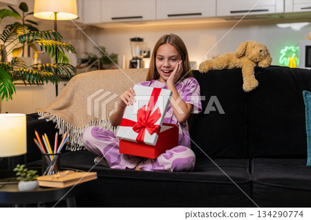 Teenager girl opens gift box joyful surprise sees wished toy inside smile excited reaction big smile 134290774