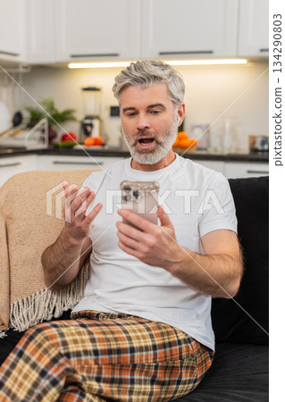 Middle-aged man practices language phrases with headphones on smartphone app repeats and feels proud 134290803
