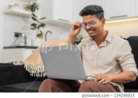 Indian man puts on glasses for clear reading of small notebook text vision focus resumes daily work Indian man puts on glasses for clear reading of small notebook text vision focus resumes daily work 134290815