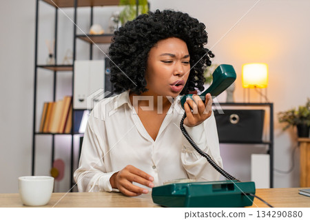 African American businesswoman yells on retro phone waving hand frustrated during angry dispute call African American businesswoman yells on retro phone waving hand frustrated during angry dispute call 134290880