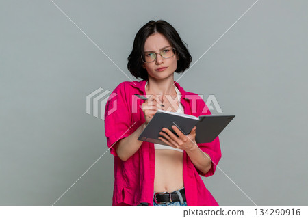 Woman thoughtfully writing in notebook carefully planning tasks making checklist organized mood Woman thoughtfully writing in notebook carefully planning tasks making checklist organized mood 134290916