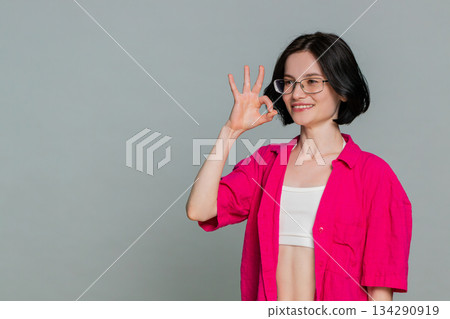 Young woman smiling nodding showing okay gesture with fingers positive approval agreement reaction 134290919