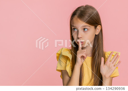 Child girl kid smiling with finger on lips making hush sign as if keeping secret asking for silence 134290936