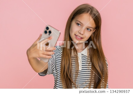 Child girl kid happily taking funny selfies on smartphone laughing joyfully making playful faces 134290937