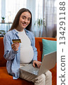 Online shopping buying pregnant woman sitting on home sofa making purchase using laptop credit card 134291188