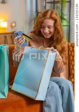 Excited young Caucasian woman with shopping bags receiving order sitting on sofa couch at home Excited young Caucasian woman with shopping bags receiving order sitting on sofa couch at home 134291190