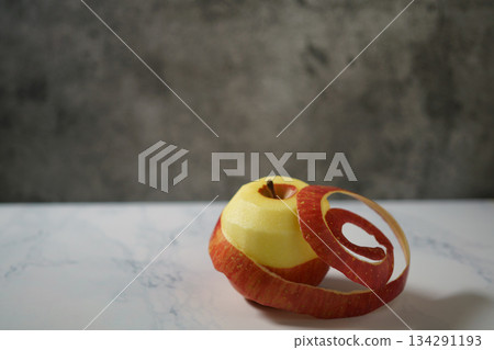 桌上放著一個削了一半皮的紅蘋果。 桌上放著一個削了一半皮的紅蘋果。 134291193