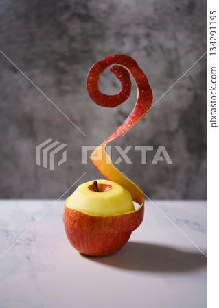桌上放著一個削了一半皮的紅蘋果。 桌上放著一個削了一半皮的紅蘋果。 134291195
