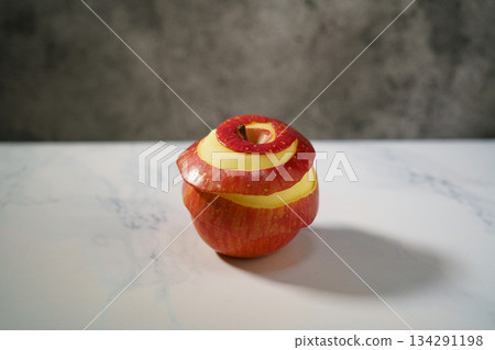 桌上放著一個削了一半皮的紅蘋果。 134291198