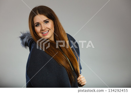 Happy woman wearing dark poncho coat with hood Happy woman wearing dark poncho coat with hood 134292455
