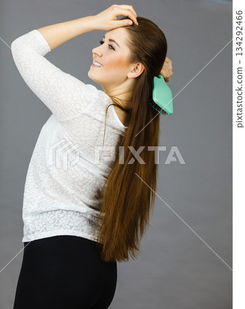 Happy woman brushing her hair Happy woman brushing her hair 134292466