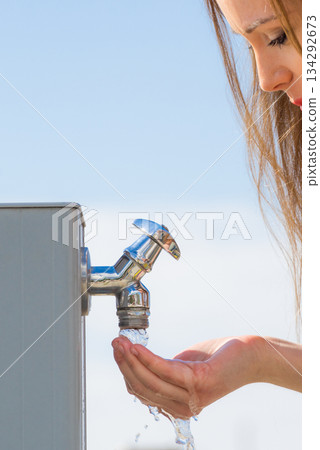 Woman drinking water from street tap Woman drinking water from street tap 134292673