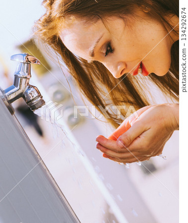 Woman drinking water from street tap Woman drinking water from street tap 134292674