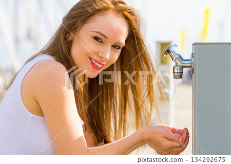 Woman drinking water from street tap 134292675