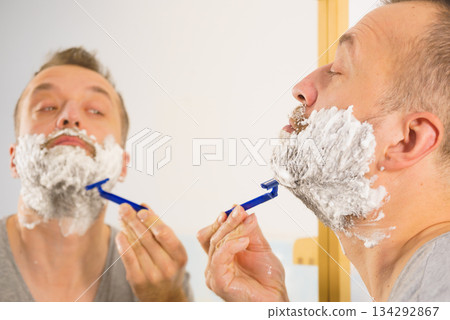 Guy shaving his beard in bathroom 134292867