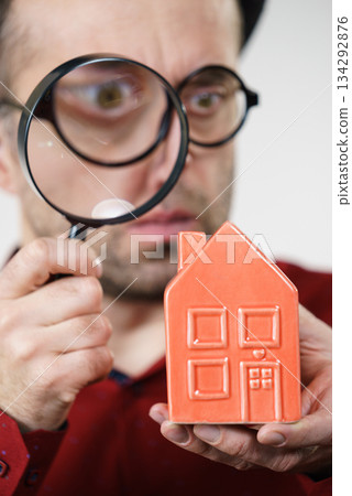 Man magnifying red house 134292876