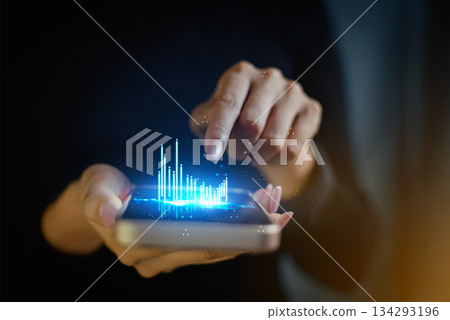 Hand holding smartphone with holographic bar chart data analysis 134293196
